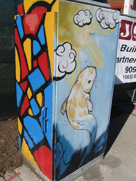 Colors like stained glass and a rising koi on this utility box.