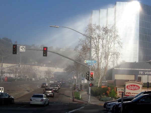 Early morning sunlight reflects from a building's windows in Mission Valley, casting heavenly beams of light through lifting fog.