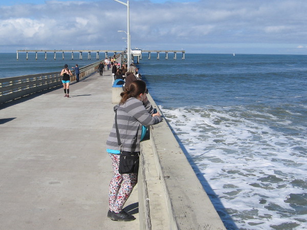 People on the pier look out across the turbulent water.