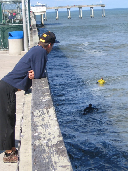 Leaning over the rail watching surfers below.