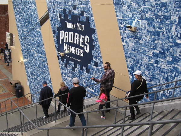 A family descends stairs near a thank you to Padres members.