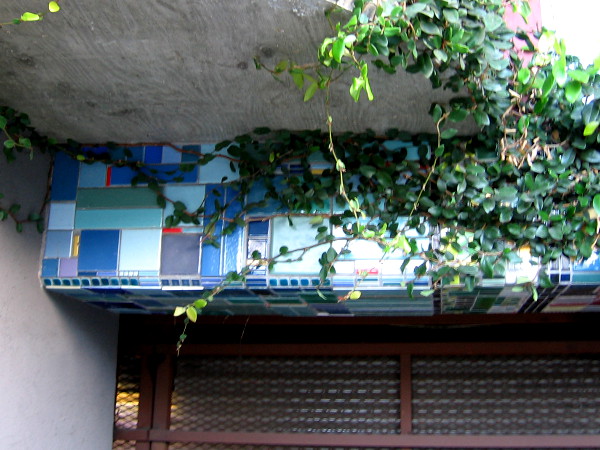 Colorful tiles beneath ivy above a garage door.