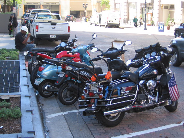 A row of motorcycles and a construction worker taking a break near Horton Plaza.