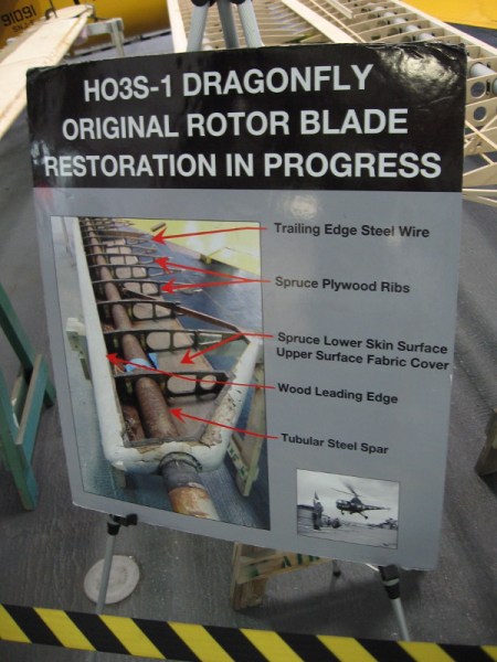 Sign on hangar deck of USS Midway describes the HO3S-1 Dragonfly's original rotor blade restoration, which is in progress.