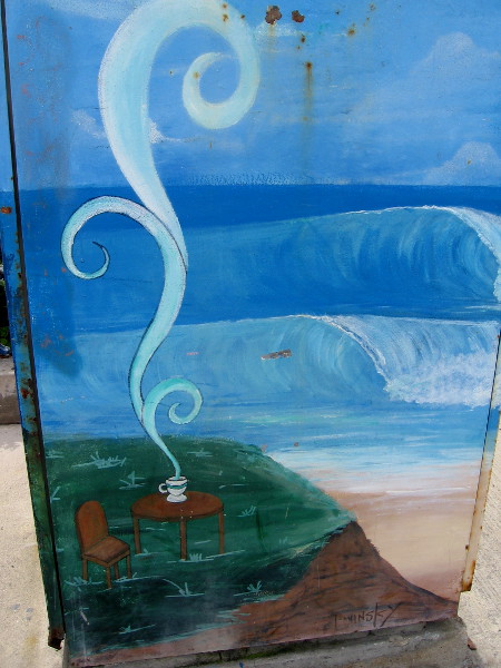 Street art on a utility box. The curl of this coffee's steam resembles the surf beyond the sand.