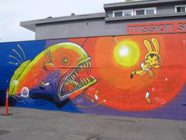 Bunny Kitty carries a cigarette butt away as a fierce sea monster emerges from the deep. Pacific Beach art created in 2016 by Dave Persue for PangeaSeed.