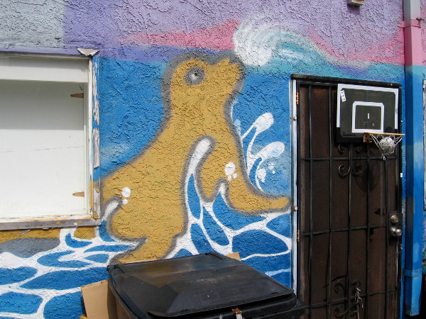 A spray painted sea lion near a door in the alley.
