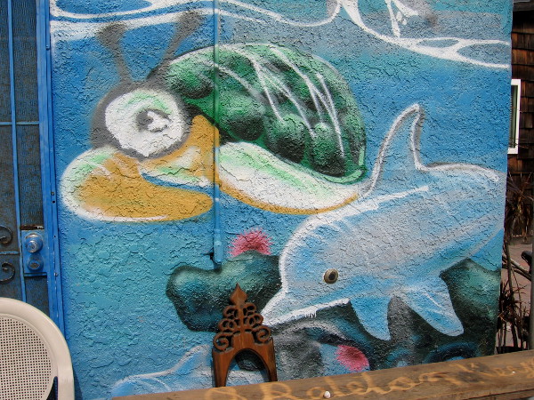 A sea turtle and dolphin swim across a wall.