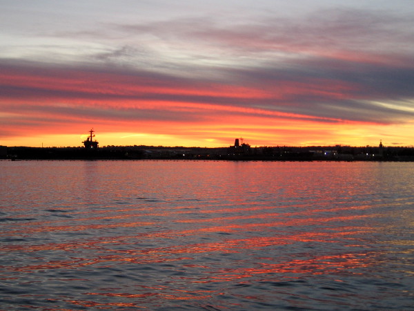 The sunset turns fiery, painting the rippled water of San Diego Bay red.
