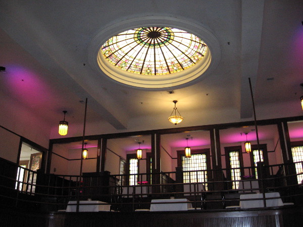 This gorgeous stained glass skylight and purple floor lights tinting the walls make a memorable dining experience at these tables on the second floor of The Abbey.