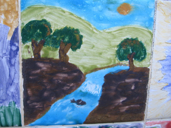 A clean river flows down from green hills between trees.