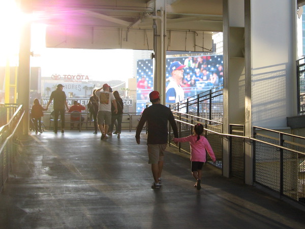 It's approaching game time. Fans walk up a ramp to the upper level.