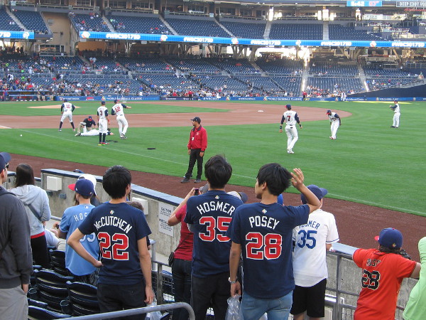 Fans of Team USA watch their baseball heroes warm up on the field before the game.