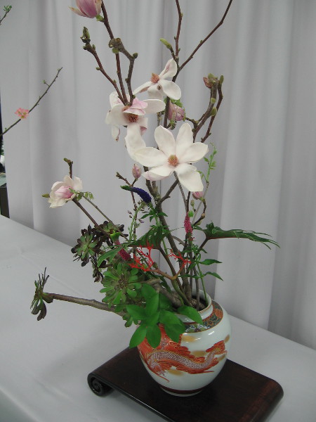 Arrangement by Noriko McDaniel. The Ohara School of Ikebana. Materials include magnolia, veronica, purple-crest aeonium, wisteria vine and philodendron.