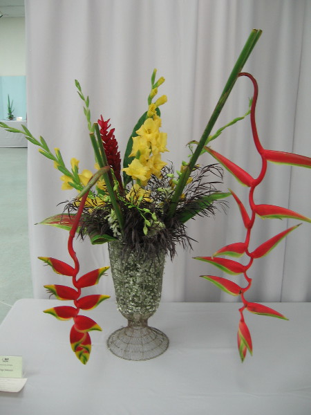 Freestyle tropical arrangement by Inge Johansen. Sogetsu School of Ikebana. Materials include heliconia, ginger, gladiolus, white orchid, variegated ti leaf.