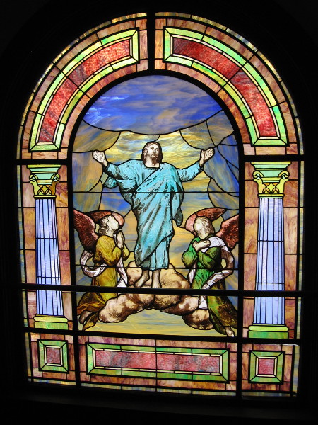 Another vibrant stained glass window portrays a risen Christ in heaven.