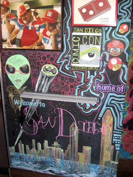 San Diego's Domino's Pizza has a fun wall with lots of pop culture imagery, including an alien, Bat signal, Mario, and the downtown skyline.