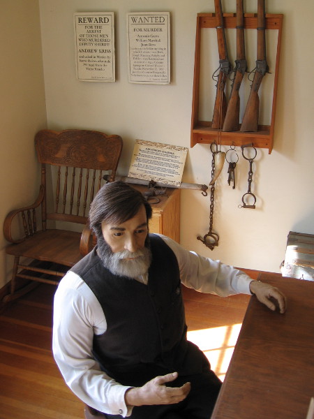 A peek into the adjacent sheriff's office. I see rifles, handcuffs and keys to the outdoor jail cell.