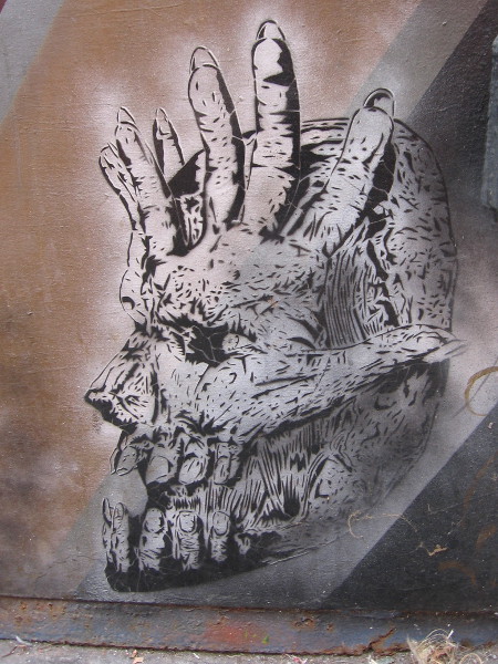 Hands and fingers create an eerie seemingly inhuman skull.