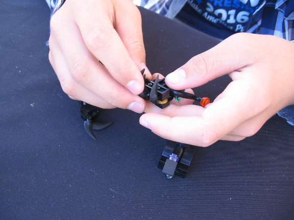 The young man demonstrates how to make an adjustment to one LEGO creation.