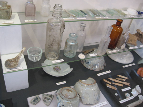 Some of many artifacts recovered include glass bottles, ceramic bowls, utensils.