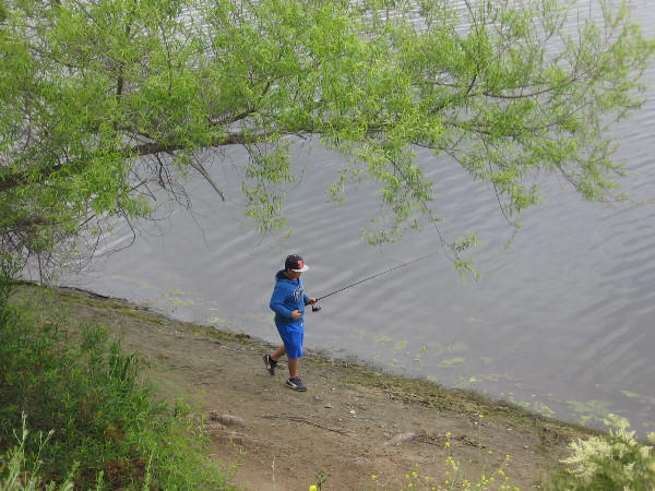 On a Sunday morning some people along the shore are trying their hand at fishing.