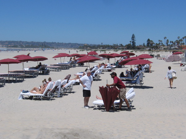Hotel guests and visitors enjoy the San Diego sunshine on a broad white beach.