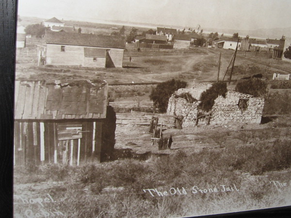 Another photo in the courtroom shows San Diego's old stone jail in a crumbling state. It stands next to the chapel cabin and the old graveyard.