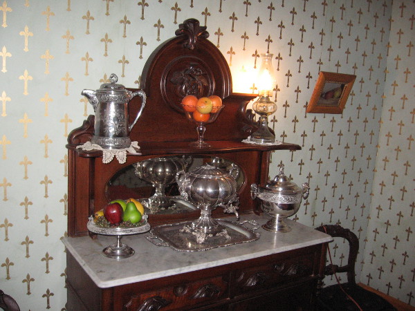 The wallpaper with fleur-de-lis patterns reflects light like a sky full of shining, golden stars. The furnishings and silver are original.