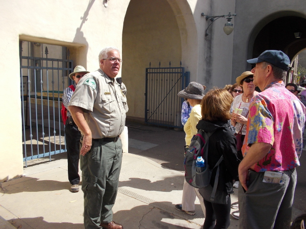 Ranger Kim relates the history of Balboa Park to a tour group. They stand by the original Administration Building, which was the first building constructed for the 1915 Panama-California Exposition.
