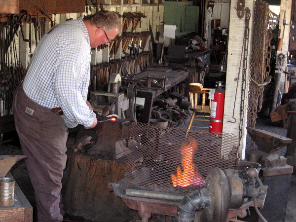 A blacksmith shapes red hot iron at a forge in San Diego's historic Old Town.