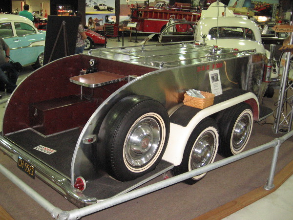 The car tows a trailer, which stores gasoline, water and oil. At the rear is an outdoor dining area!