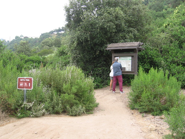 Hikers read the sign at the Battle Trail trailhead.