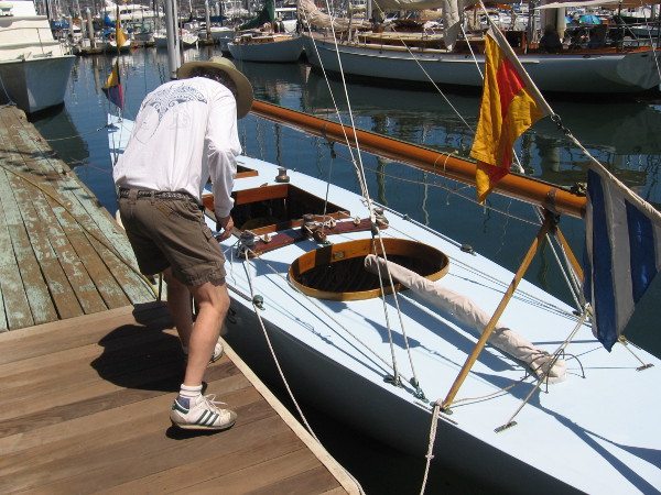 Someone peers down into a beautiful wooden sailboat.