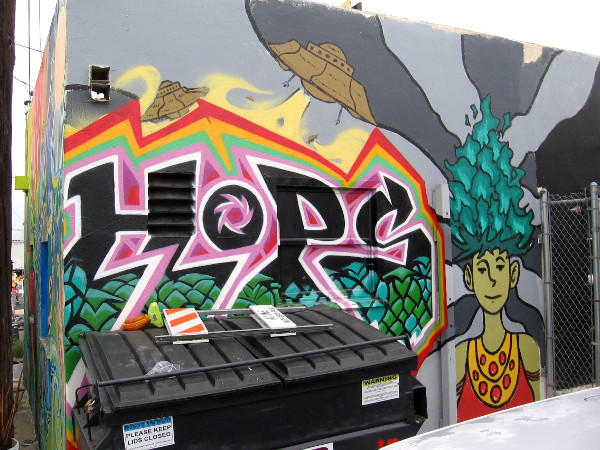 Hope, flying saucers and flaming green hair, part of a second mural on two walls in the same alley.