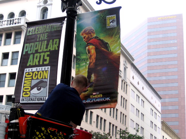 Workers hang San Diego Comic-Con banners along Fifth Avenue in the Gaslamp Quarter.