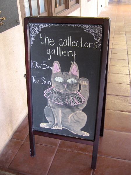 A chalk cat in Balboa Park waves to passing visitors. Fun art outside the Mingei Museum's Collectors Gallery.
