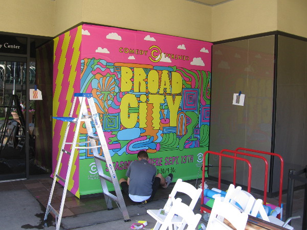 Someone paints a graphic along MLK Promenade promoting Broad City on Comedy Central.