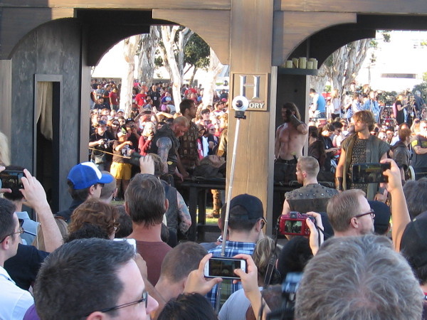 A fallen warrior is ready to be carried from a small fortress-like Viking building.