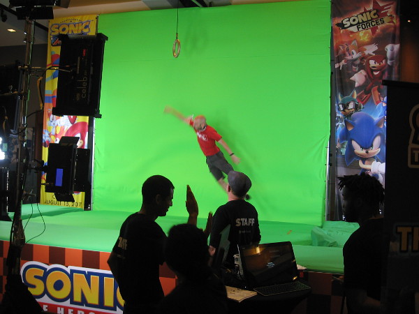 The Sonic the Hedgehog booth had people jump for a ring in front of a green screen for prizes. They could see themselves in a video game.