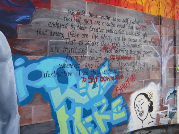 Declaration of Independence on a wall, altered to condemn instances where power is abused.