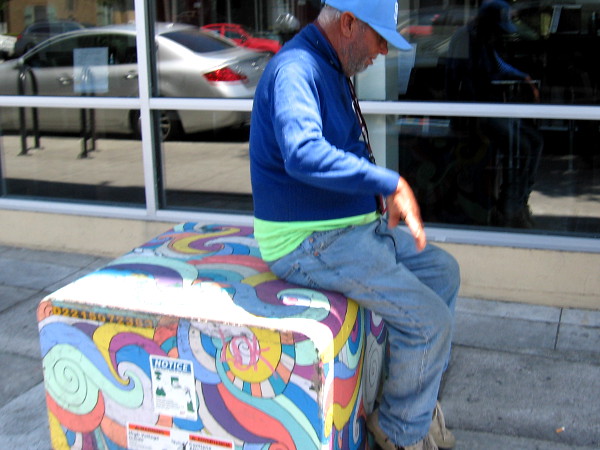 Someone rests on a painted transformer box on Adams Avenue near 30th Street.