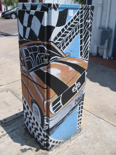 A classic car and tire tracks painted on a utility box on the sidewalk in front of Tire Depot.