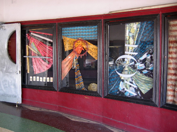 Fabric art in windows of the old theater, where movie posters were once displayed.