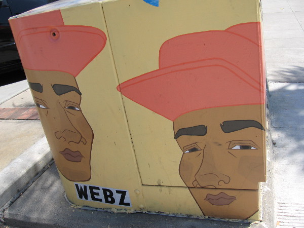 Two faces watch people walking down the sidewalk.