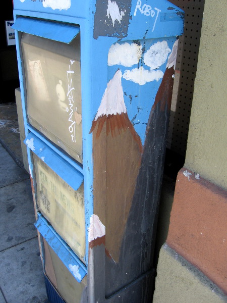 A snow-capped mountain peak on the side of a newspaper box.