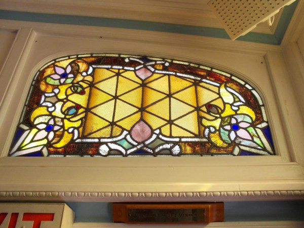 Different stained glass windows on the ship infuse the passenger deck with colored light.