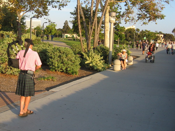 Walking very slowly, rhythmically, toward Ruocco Park, playing bagpipes.