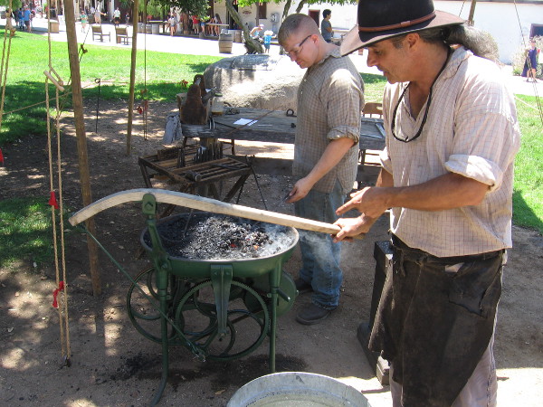 This portable green forge is being used for the first time. The handle turns a belt which operates an air blower. I recognized this blacksmith from the Fall Back Festival in San Diego's Gaslamp Quarter.