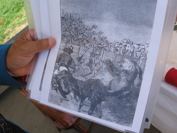 A gentleman who teaches students visiting Old Town about history holds up an illustration of bear-baiting, which early Californians found entertaining.